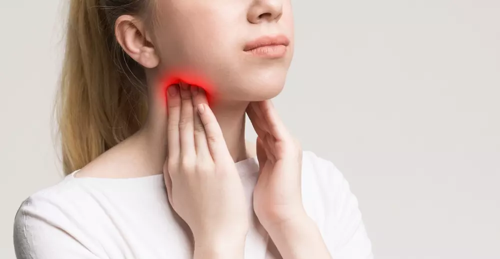 Tiroid bezlerini tutan kadın